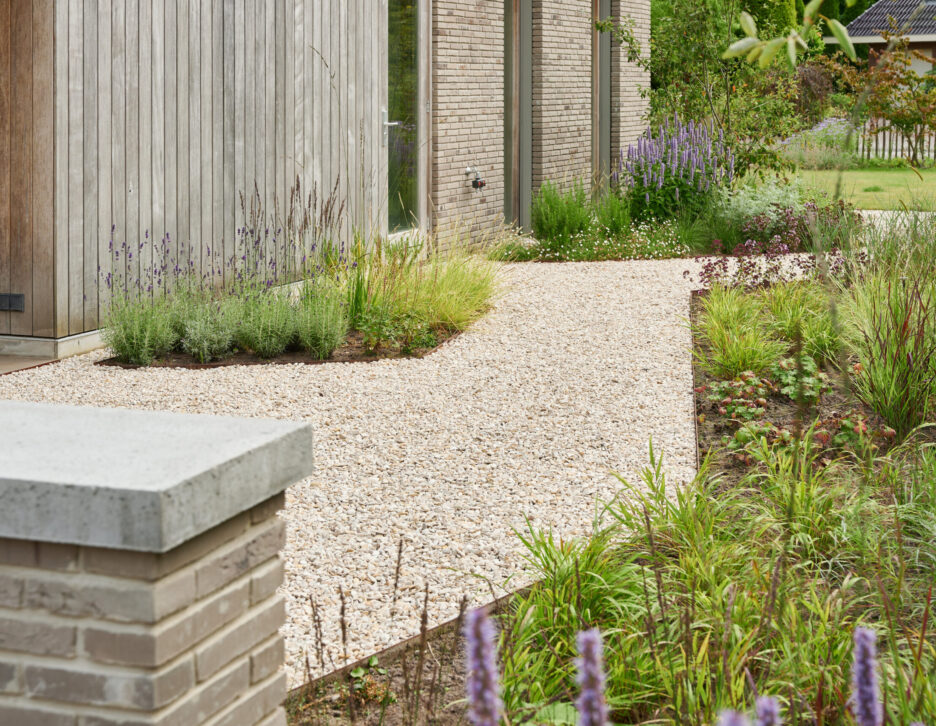 Grindpad omgeven door bloemrijke borders in tuin
