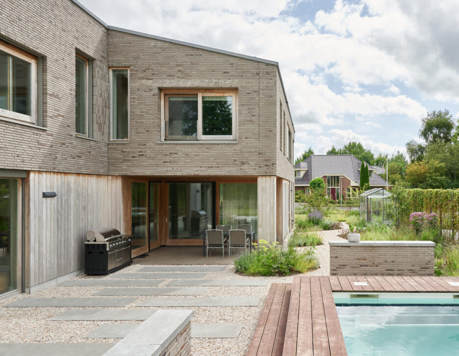 Grindpad met Schellevis-stapstenen langs modern zwembad in tuin
