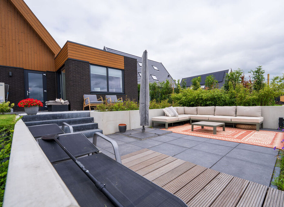 Hoveniers Collectief - tuin met terras aan het water Moderne tuin met terras van tegels en hardhouten vlonder aan het water