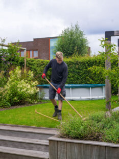 Hoveniers Collectief - Onderhoud Tuinonderhoud: man verwijdert onkruid met een schoffel