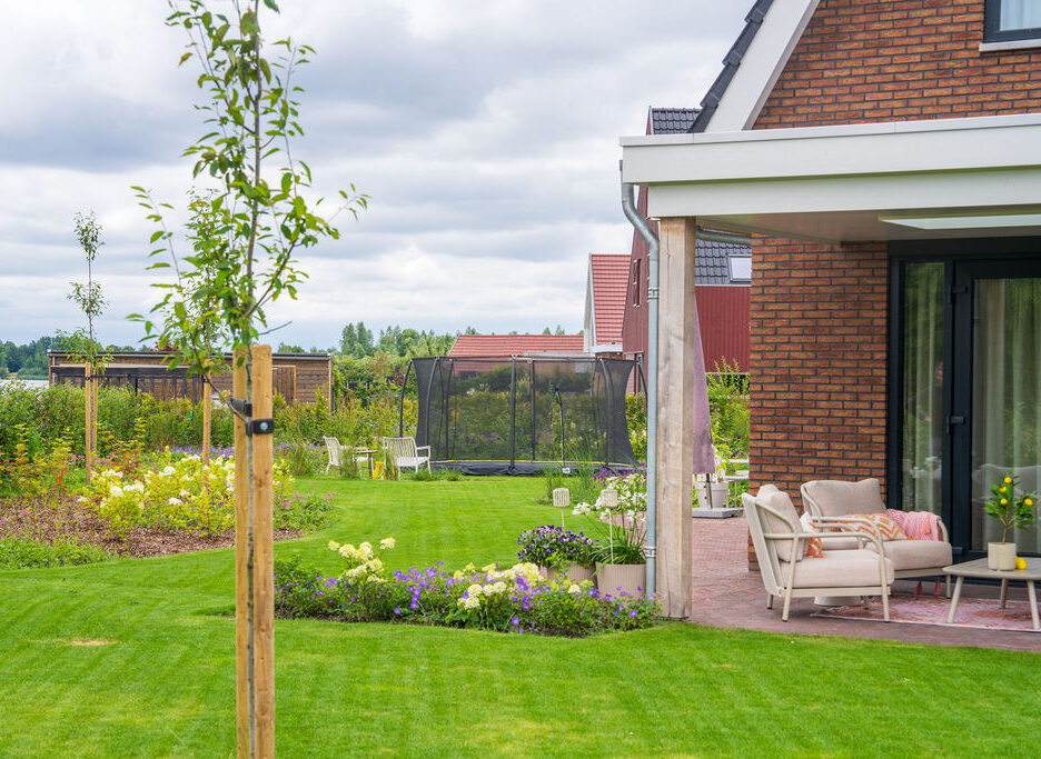 Hoveniers Collectief - landelijke tuin met bomen, borders, gras en terras Landelijk tuinontwerp met bomen, borders, gazon en terras