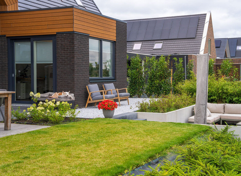 Hoveniers Collectief - tuin aan het water Moderne tuin met zitplekken aan het water en groen terras