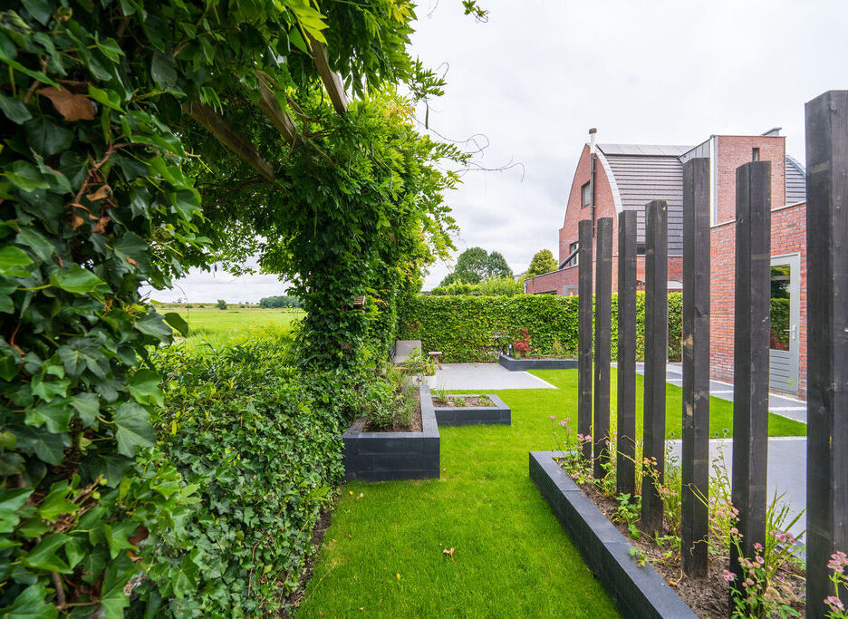Houten decoratiepalen in een moderne stadstuin als sfeerelement en afscheiding.