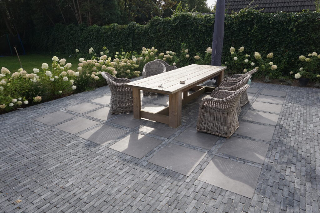 Terras met een combinatie van klinkers en keramische tegels in de tuin