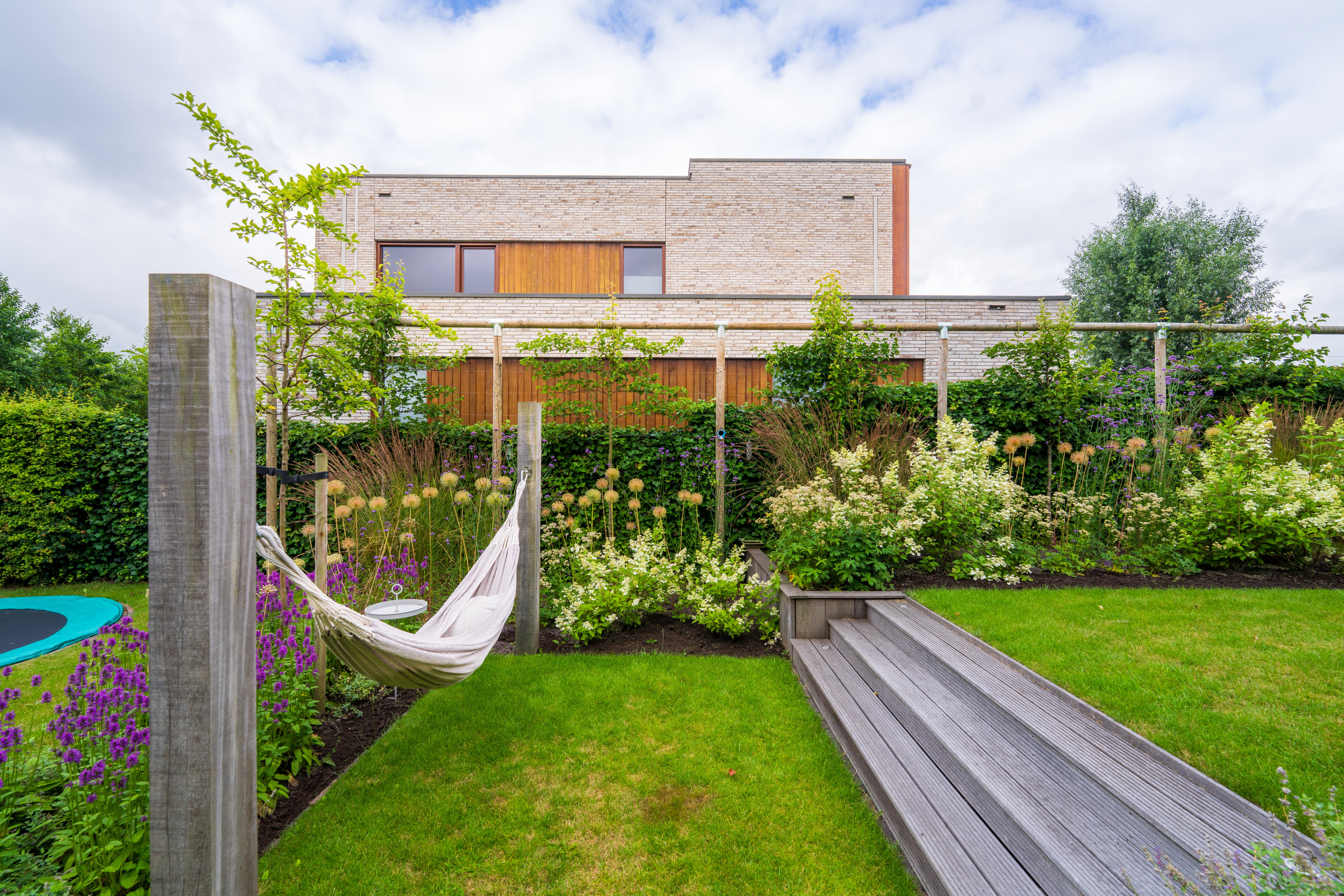 Hangmat aan Douglas palen in natuurtuin met bloemrijke borders